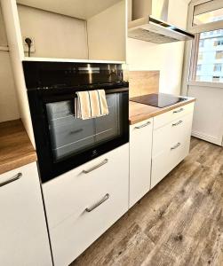 eine Küche mit einem schwarzen Backofen und weißen Schränken in der Unterkunft Le petit savoyard in Albertville + 3 Fotos
