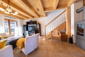 una sala de estar con techos de madera y una escalera. en Haus Alpenruhe, en Königsleiten