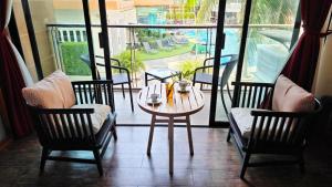 Beautiful Pool View Studio in Kata في شاطئ كاتا: طاولة وكراسي في غرفة مطلة على الفناء