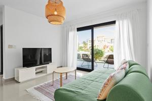 a living room with a green couch and a television at The G Cribs Sunlit - El Gouna in El Gouna