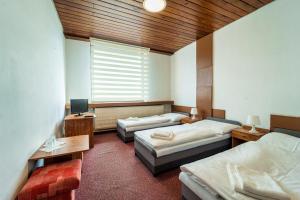 ein Zimmer mit drei Betten, einem Schreibtisch und einem Fernseher in der Unterkunft Hotel Slovakia in Žilina + 43 Fotos