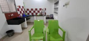 two green chairs in a kitchen with a counter at Ashwin Home Stay in Tiruvannāmalai
