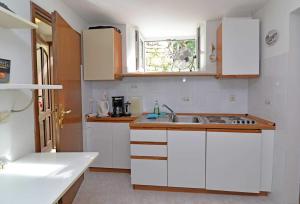a kitchen with white cabinets and a sink and a window at Studio Veli A in Veli Lošinj