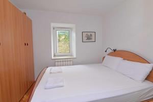 a bedroom with a large white bed with a window at Studio Veli A in Veli Lošinj