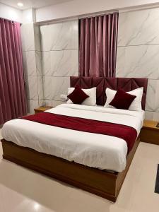 a bedroom with a large bed with red curtains at Hotel the grand pritam in Gandhinagar