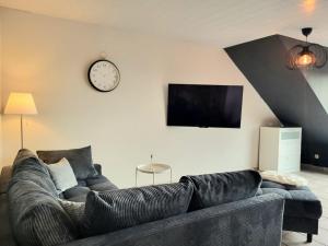 a living room with a couch and a clock on the wall at Weltmann`s Hotel & Restaurant in Ennepetal