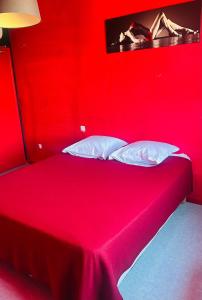 ein rotes Bett mit weißen Kissen in einem Zimmer in der Unterkunft L'Acro Love in Nissan-lez-Enserune