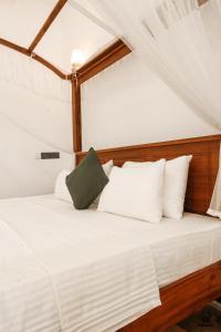 a bed with white sheets and a green pillow on it at Plant Mama Guest House in Weligama