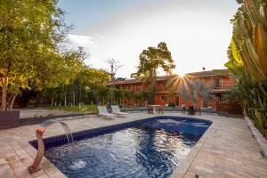 a swimming pool with a water fountain in a yard at Pousada In Bali - Maresias in Maresias