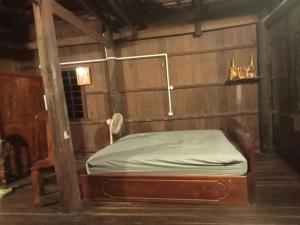 una cama en una habitación con una pared de madera en Sconvolt Homestay, en Kratié