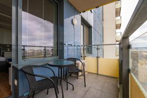 City Bright Apartment with Parking & Balcony في Trnávka: شرفة مع طاولة وكراسي ونوافذ