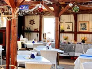 un restaurante con mesas blancas y sillas blancas en Ankes Pension "Koje 7", en Rostock