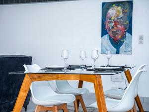 Appartement Cosy avec Balcon - Haie Vive في كوتونو: طاولة طعام مع كراسي بيضاء ولوحة