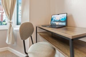 a laptop computer sitting on a wooden desk with a chair at Contractors, Free Parking, TV, Discounts, Wi-Fi in Wallasey
