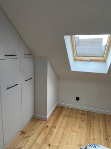 an attic room with a skylight and wooden floors at Apartament na lipowej in Pastwiska