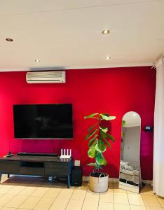 a living room with a red wall with a flat screen tv at Suider home stay in Johannesburg