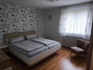 een slaapkamer met een bed, een stoel en een raam bij Ferienwohnung Angelika Zimmermann Dettelbach in Dettelbach