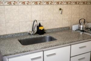 a kitchen counter with a sink and a stove at Keóken a la vuelta del casino in Caleta Olivia