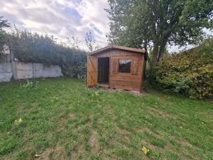 a small wooden shed in a field of grass at Le Refuge des Dunes in Bray-Dunes