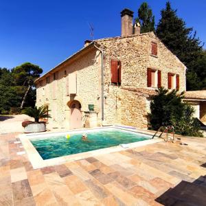 a house with a swimming pool in front of a building at Gites L INSTANT PRESENT CHEZ LO in Visan