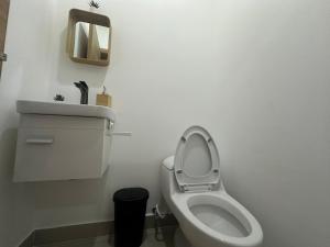 a white bathroom with a toilet and a mirror at Ecos del Mar 2 - Villa 7 · Modern 2BR Villa in Downtown Punta Cana in Punta Cana