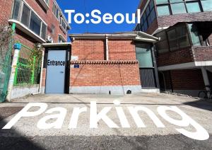 To Seoul Stay with 1-Story House near Itaewon Stn 5min walk في سول: لافته امام مبنى فيه موقف