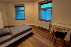 Wohnung zentral zwischen Gladbeck und Buer في غلادبك: غرفة نوم بسرير وكرسي ونوافذ اثنين