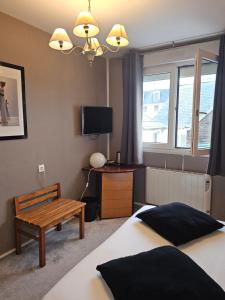 a bedroom with a bed and a bench and a tv at Hôtel 1er Consul Rouen in Rouen