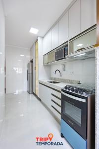 a kitchen with a stove and a refrigerator at Apartamento espaçoso com ar condicionado e Wi-fi, a 100 metros da praia - Edifício Estoril in Ubatuba