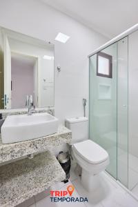 a white bathroom with a sink and a toilet at Apartamento espaçoso com ar condicionado e Wi-fi, a 100 metros da praia - Edifício Estoril in Ubatuba +34 photos