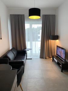 a living room with a black couch and a tv at Apartament Kołobrzeska 2 in Piła