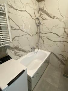 bagno con lavandino bianco e parete in marmo di Apartament Kołobrzeska 2 a Piła