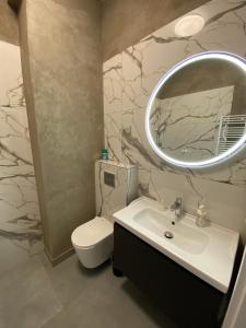 un bagno con un water, un lavandino e uno specchio di Apartament Kołobrzeska 2 a Piła