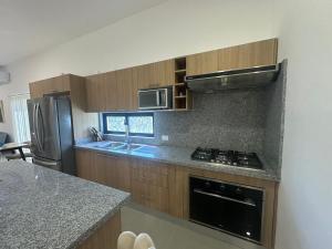 a kitchen with wooden cabinets and a stove top oven at Ecos del Mar 1 - Villa 31 · 3BR Tropical villa near Downtown in Punta Cana