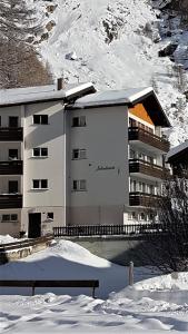 ein Gebäude im Schnee vor einem Berg in der Unterkunft Appartement Lehnbach in Saas-Almagell