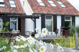 a house with a deck with flowers in the yard at De Woeste Wieven op Erve Bonkert in Diepenheim