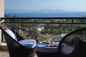 a balcony with two chairs and a table with a drink at Iakovakis Suites & Spa in Koropi