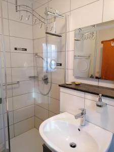 a white bathroom with a sink and a shower at Appartement am Waldeck in Hauzenberg +18 photos