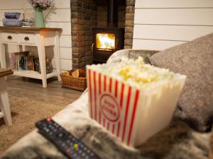 a box of popcorn sitting on a couch with a remote control at Gingerbread Cottage - Part of the The Bay Filey Holiday Village with pool, gym and direct beach access, pub, restaurant, tennis and meadows walks in Filey