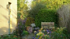 ein Garten mit zwei Bänken und Blumen in der Unterkunft Maisonette Apartment In Historic Paretz in Paretz
