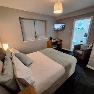 a bedroom with a bed and a chair and a television at Luxurious Double En-Suite Tralee Town Centre in Tralee