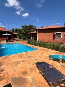 una piscina con due sedie a sdraio accanto a una casa di Chácara Recanto Verde - Condomínio Vitassay- Boituva a Boituva