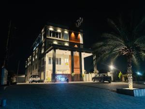 a building with a palm tree in front of it at night at 69th Heaven Hotel in Devanhalli