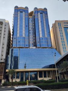 ein großes blaues Gebäude mit einem davor geparkten Auto in der Unterkunft فندق المسار العزيزية in Mekka