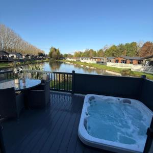 a hot tub sitting on a deck next to a river at White Swan Lodge in Allerthorpe