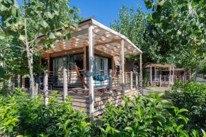 a wooden cabin with a porch in the woods at Camping Riccione in Riccione