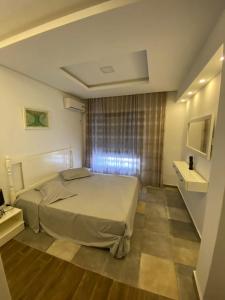 Un dormitorio con una cama grande y una ventana. en Duplex Rim ,with swimming pool, en Ḩammām al Ghazzāz