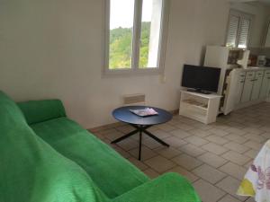 a living room with a green couch and a table at Gîte Acacia in Rosières