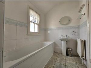 Spacious Home - Solihull Town Centre- Near NEC-BHX في سوليهال: حمام أبيض مع حوض وحوض استحمام ومغسلة