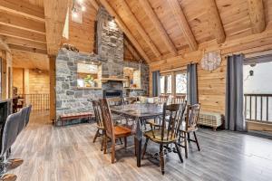 a dining room with a stone fireplace and a table and chairs at Chalet La Source Rouge in Saint-Raymond